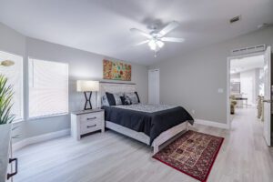 Modern bedroom with bed, rug, and ceiling fan.