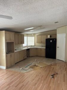 Empty kitchen with beige cabinets and fridge.
