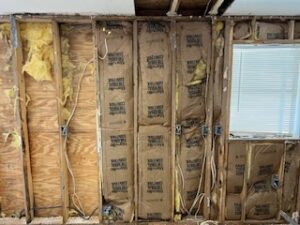 Exposed wall with insulation and wiring visible.